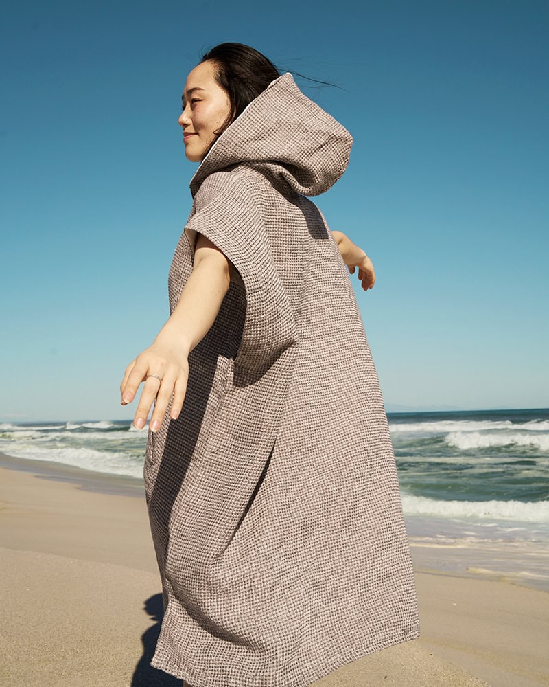 Model wearing the Oyster Linen Beach Poncho by Mungo on the beach