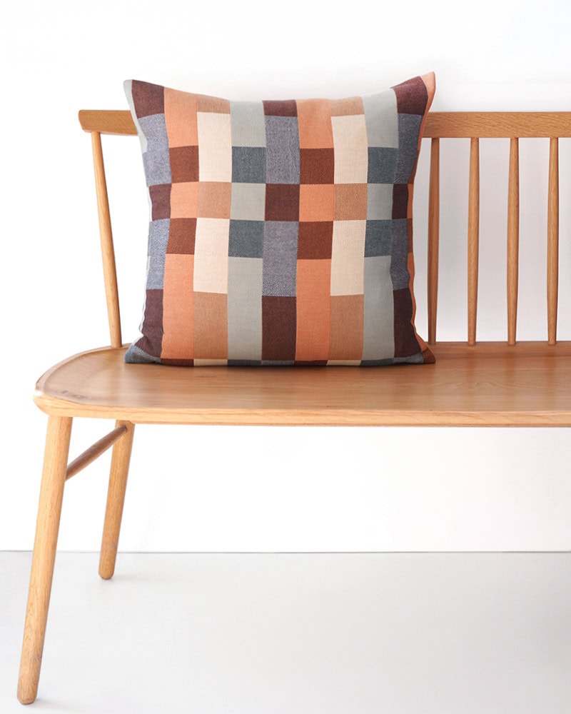 The Wild Fire Double Cloth by Mungo on a bench, displaying its orange, copper, and sky blue tones.