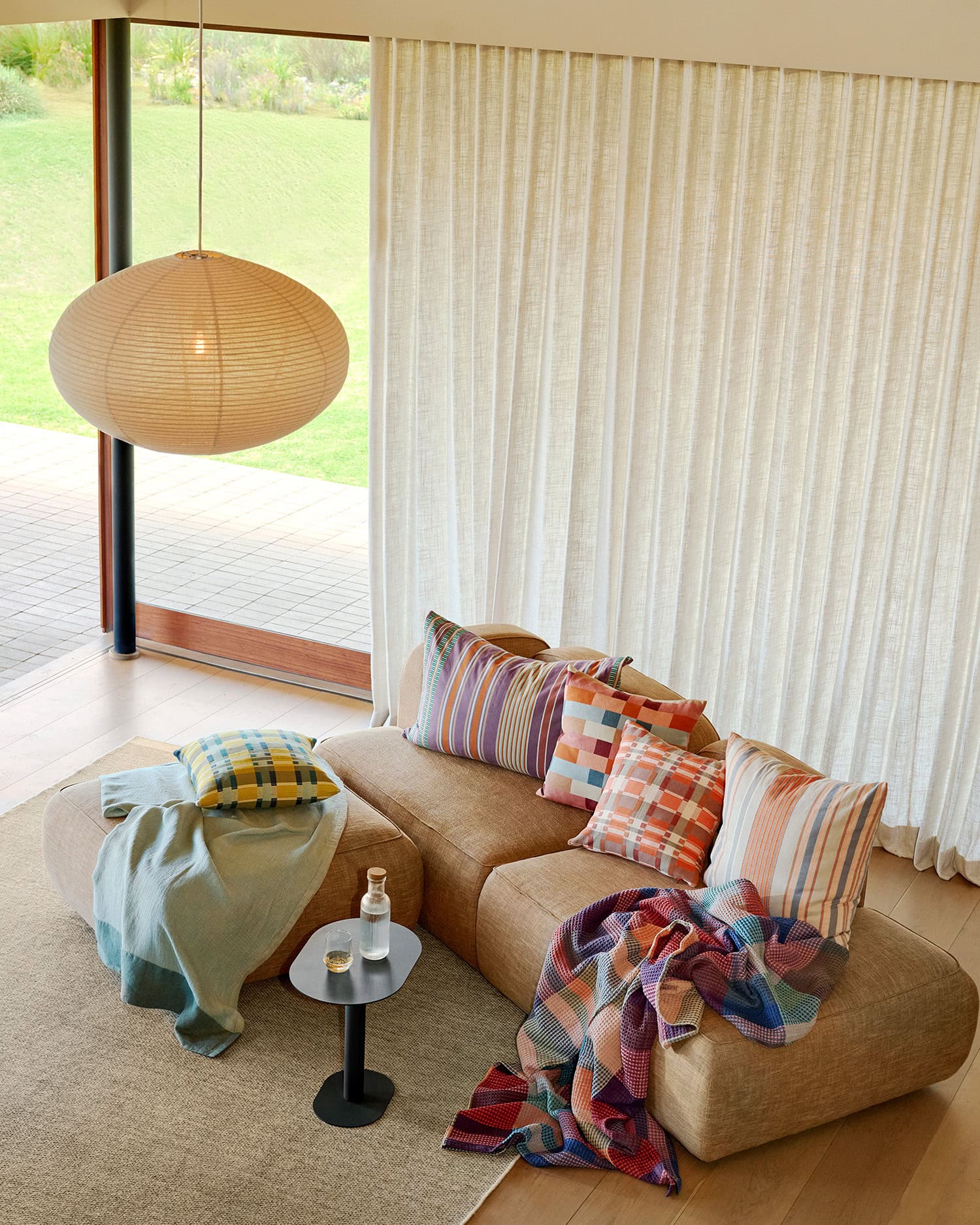 Lounge view with a selection of Mungo cushions and blankets on a couch.