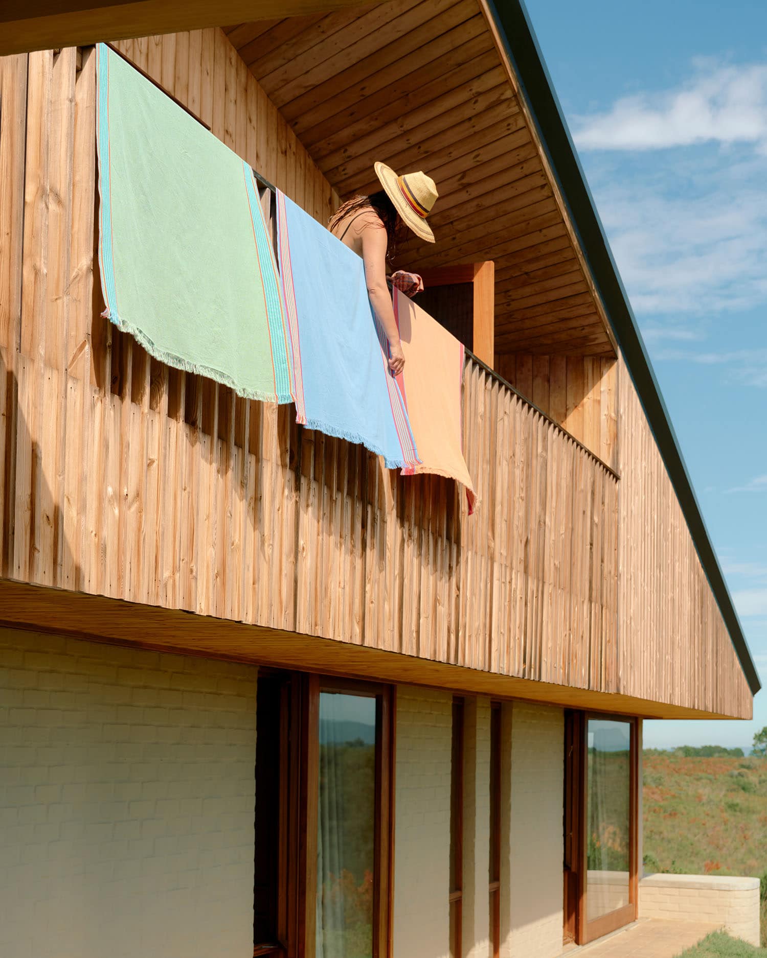 Model stanind on a balcony hanging the Mungo Ruti Kikois over the railing.