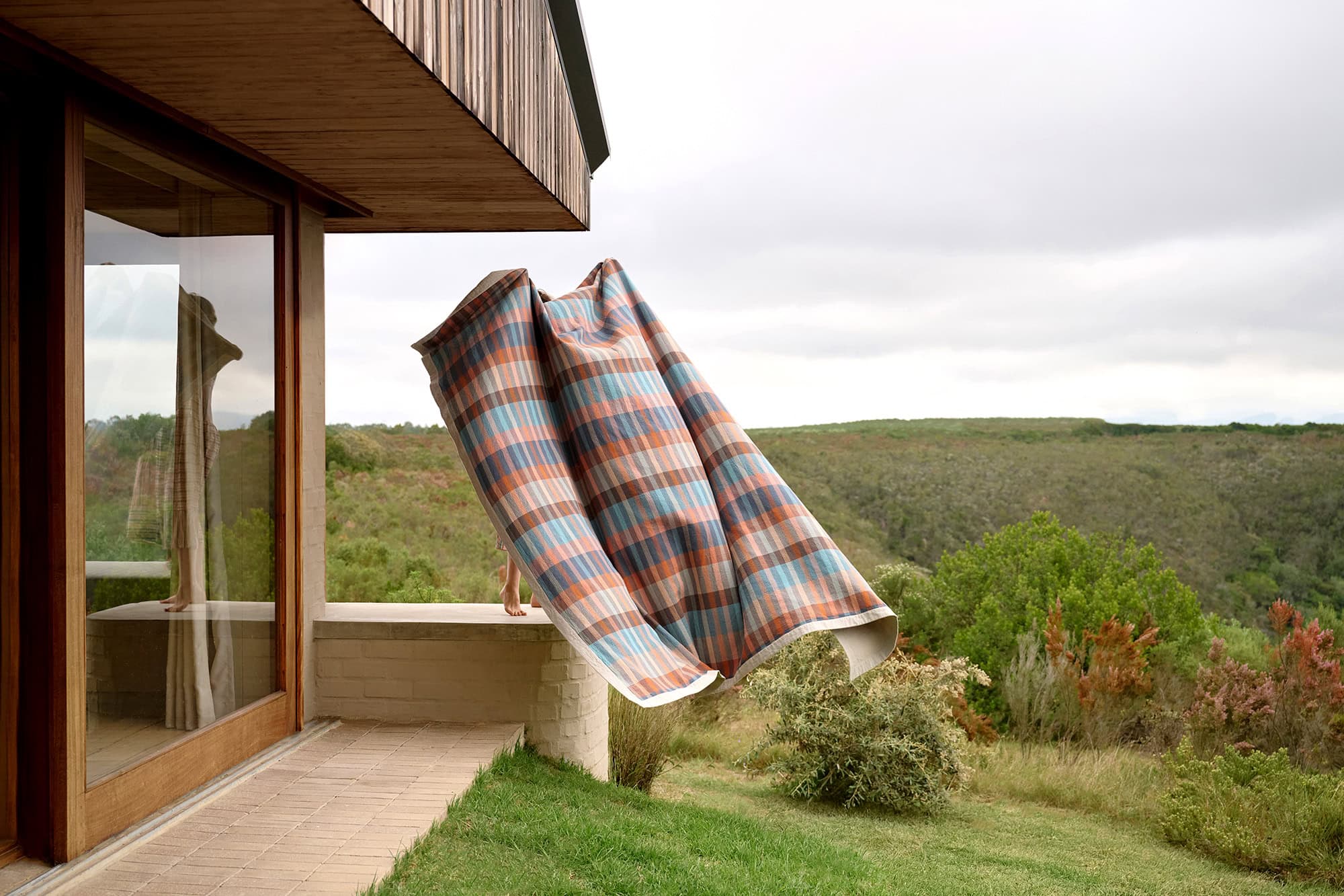 Model holding a Mungo Duo blanket in Mesa billowing out in the wind.