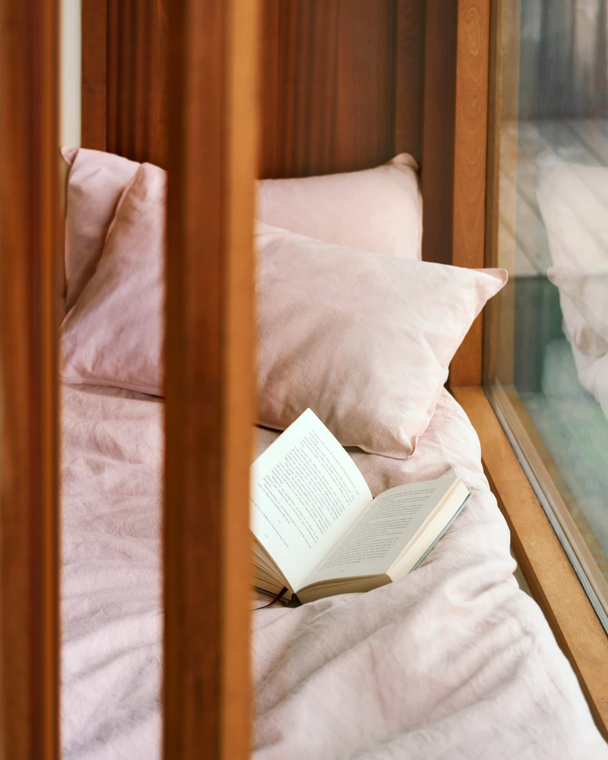 Mungo Union cloth bed linen in pink by a window.