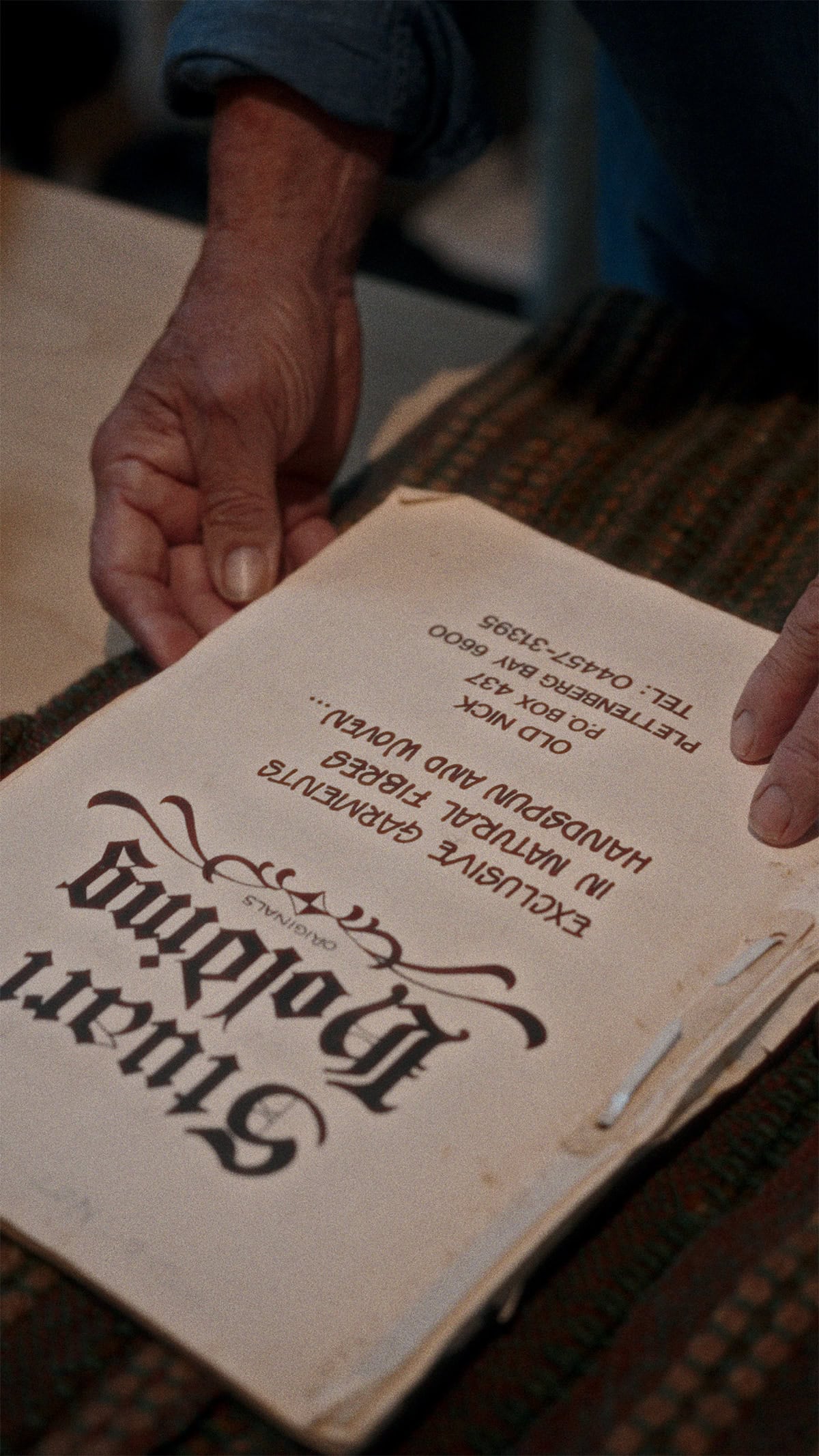 Stuart Holding holding a a book he wrote on weaving in 1970s.