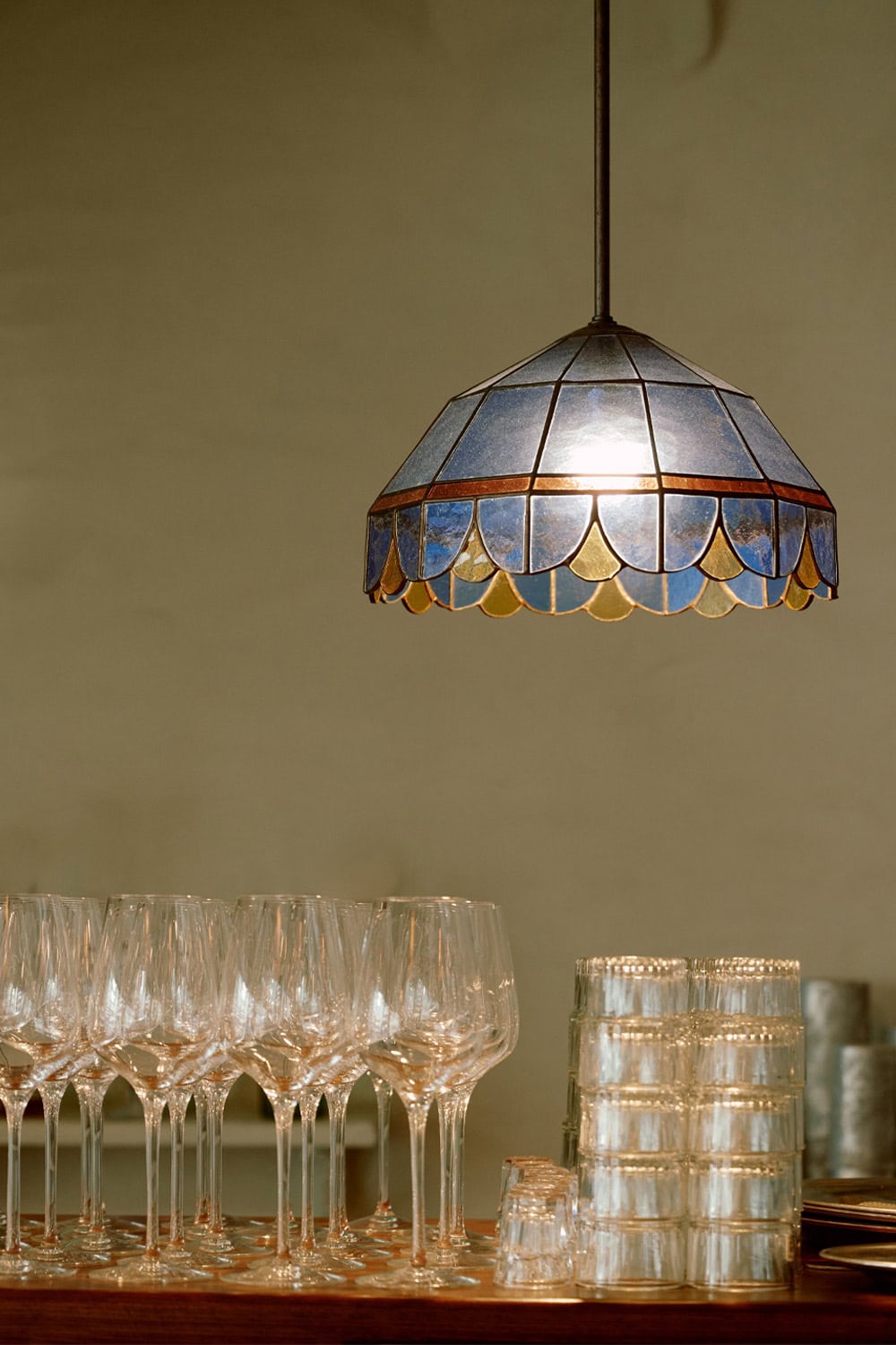 Ouzeri restaurant with a pendant light and glasses.