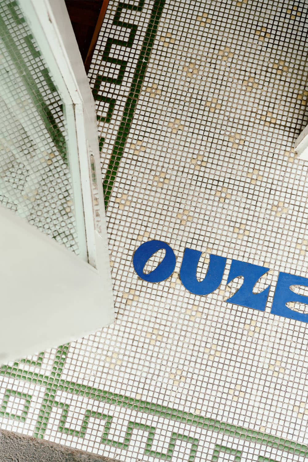 The entrance to Ouzeri restaurant entrance with a with mosaic floor.