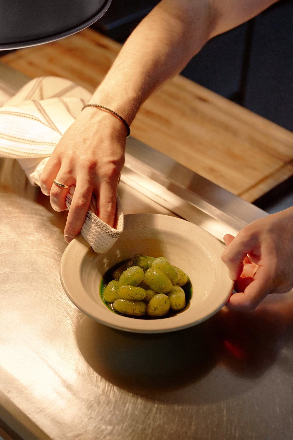 Chef wiping a Ouzeri dish of green tomatoes with a Mungo Natural Cotton Waffle Weave.